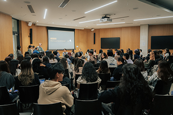 In a crowded lecture hall, an audience of students participates in an icebreaker activity